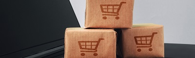A close up photo of brown paper cartons with shopping cart stamp sitting on lap top
