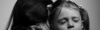 A close up of a duaghter hugging her mother with sad scruched up face to camera