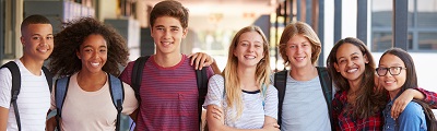 A group of young people smiling at the camera standing in a school hallway